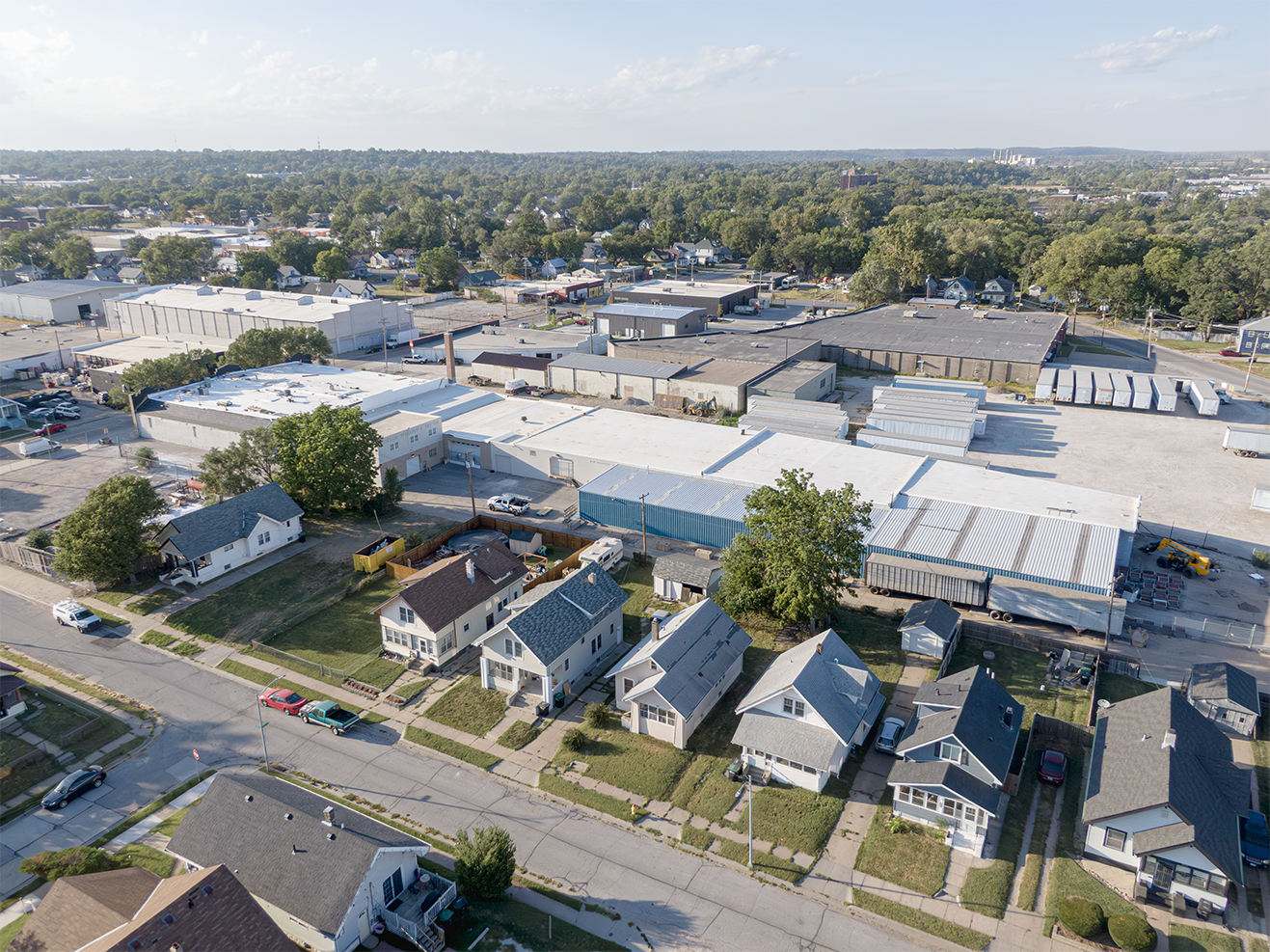 Aerial view of a large industrial roof completed by Roof Rite. The expansive white roofing system provides energy efficiency and long-term protection for the commercial facility at the center of the frame. Residential houses line the bottom of the frame, highlighting the scale of the job.