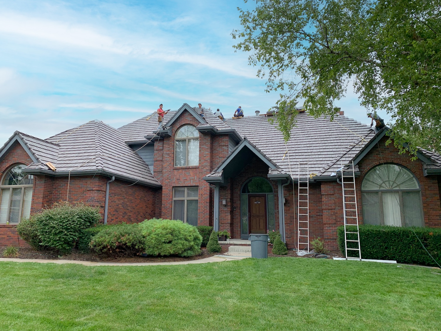 Roof Rite workers installing a Davinci Composite Shake roof in Weathered Gray on an affluent, colonial style, brick house.